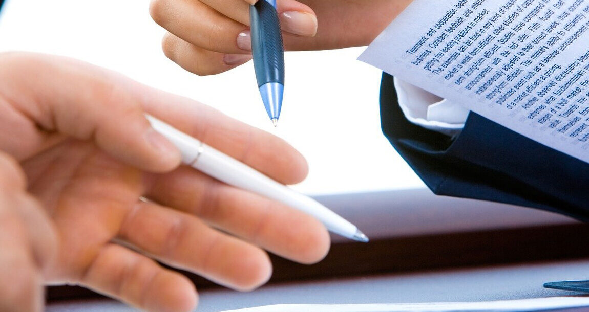 met de pen in de hand buigen man en vrouw zich over een contract
