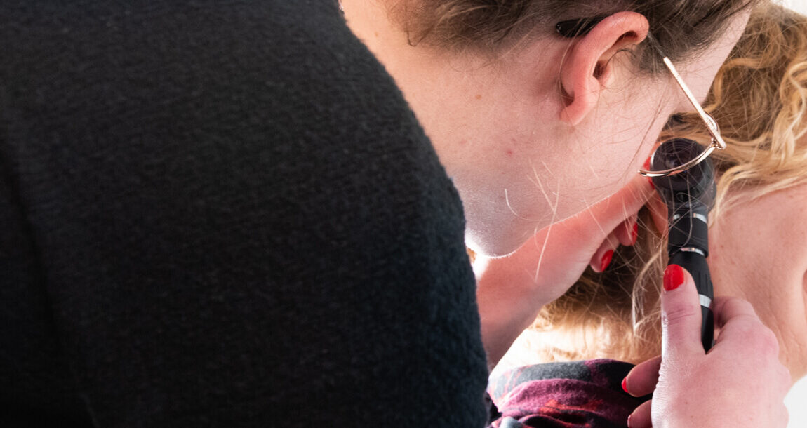 doktersassistente kijkt in het oor van een patiënt