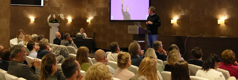 congreszaal met leden die kijken naar een presentatie van Sander Duivestein