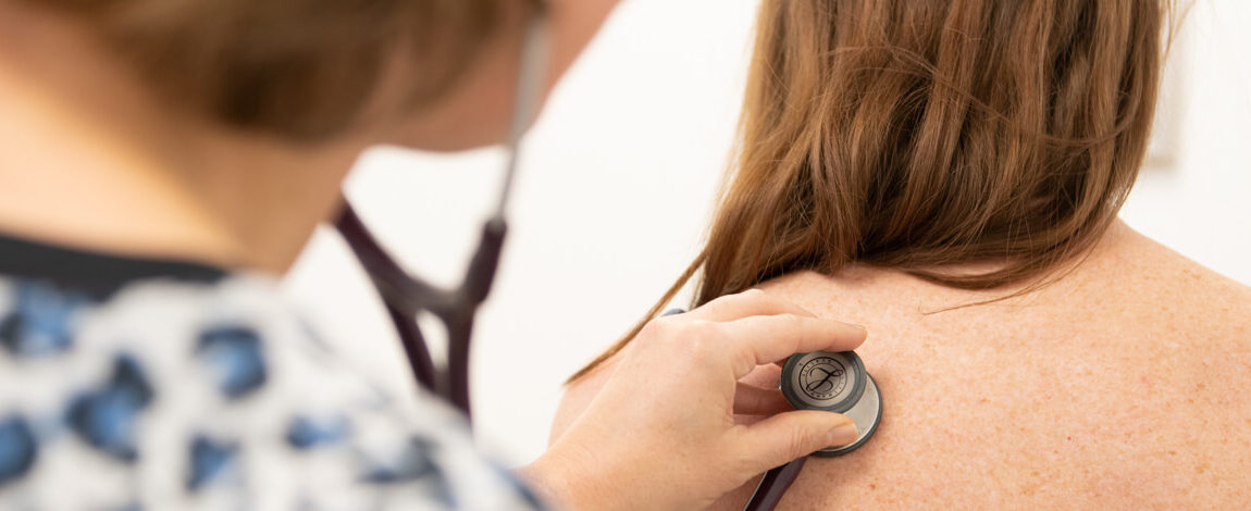 Arts luistert met stethoscoop op de rug van een patient
