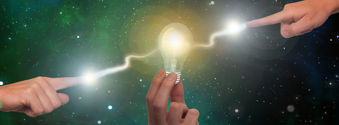 Twee handen wijzen in elkaar's richting. Er onstaat een lichtflits tussen beide handen vanuit de vingertoppen. Een derde hand houdt er een lampe tussen en deze gaat branden.