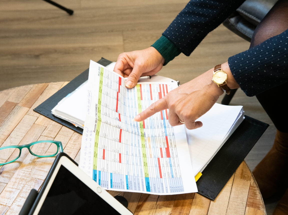 Handen die wijzen naar een uitgeprint excel bestand