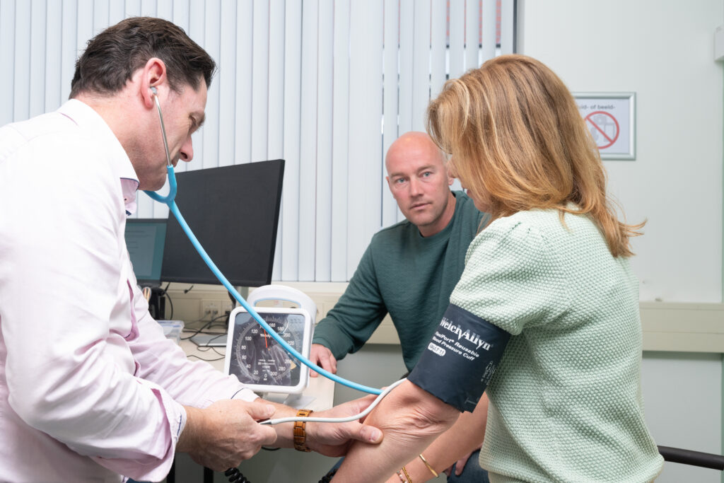 Huisarts neemt bloeddruk op bij patient