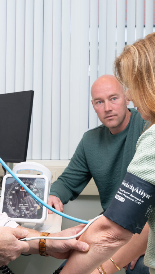 Huisarts neemt bloeddruk op bij patient