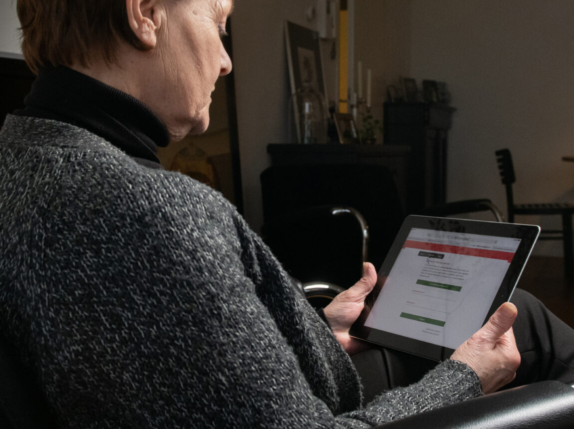 Vrouw kijkt geconcentreerd op haar tablet.