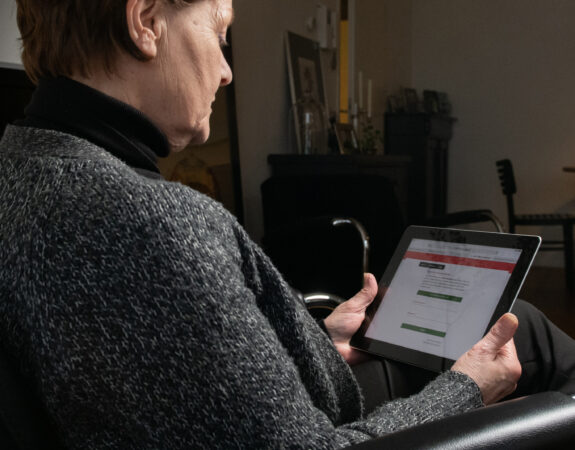 Vrouw kijkt geconcentreerd op haar tablet.