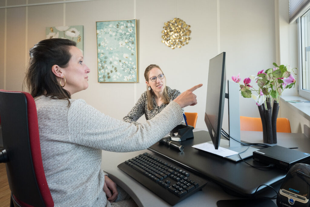 vrouw wijst naar beeld in spreekkamer, is met patiënt