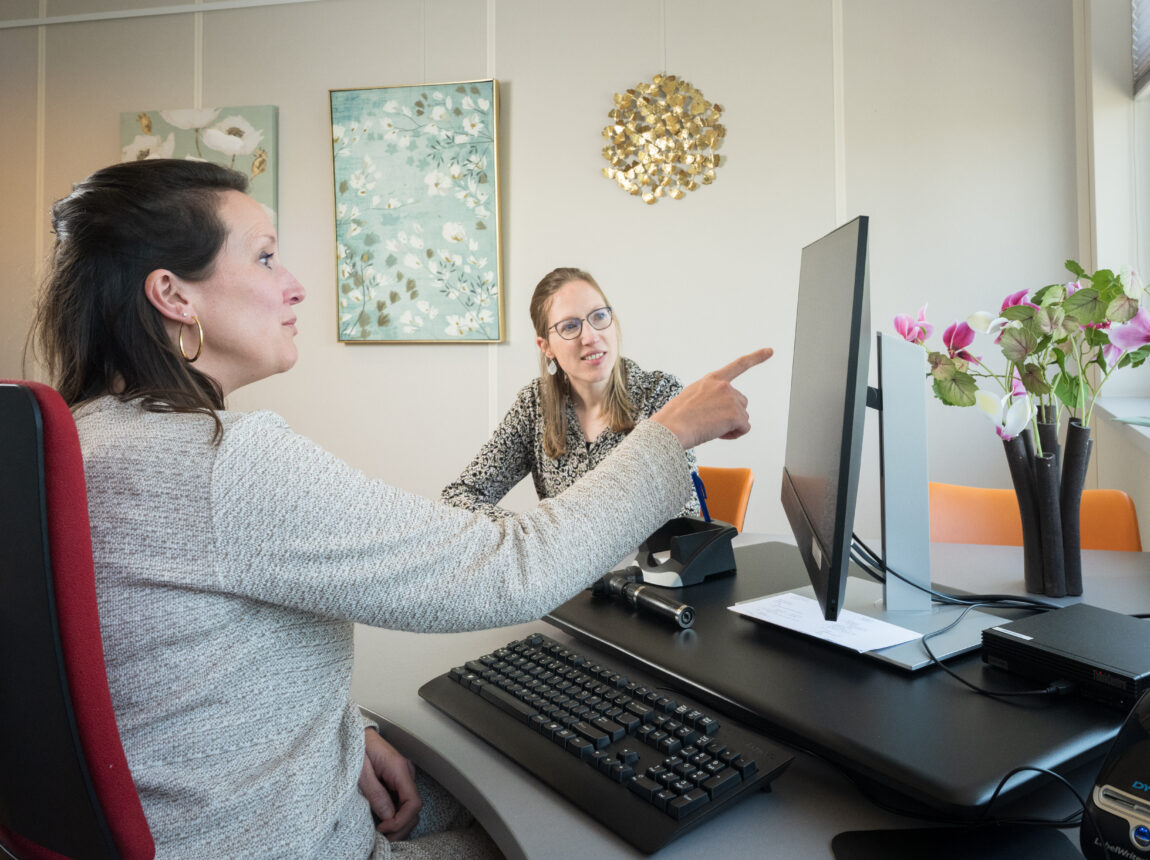 vrouw wijst naar beeld in spreekkamer, is met patiënt