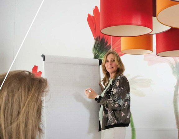 Vrouw die bij een whiteboard voor een groep staat