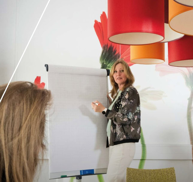 Vrouw die bij een whiteboard voor een groep staat